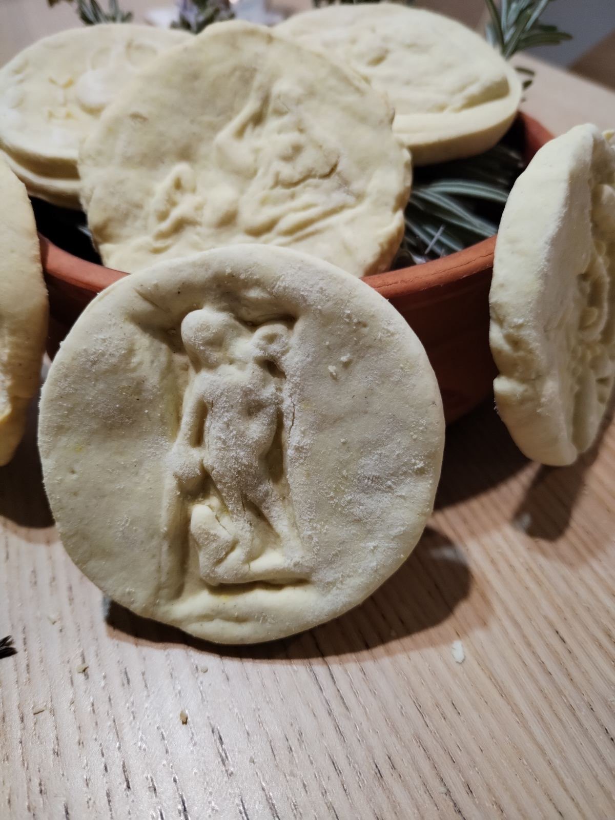Original phone photo from the client: a pale Amulum cookie with a standing Roman figure, leaning on a clay bowl